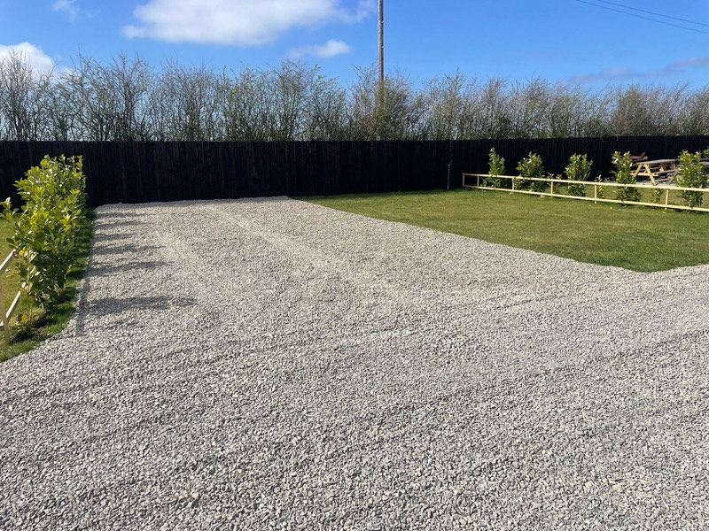 Level gravel hard-standing touring pitch with fresh fencing at Stag Park